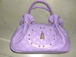 Lady beauty handbag supplier imports for wholesale. Designer inspired purple purse has double crisscross stitching, cinched sides, and studded oval shape in front with lock