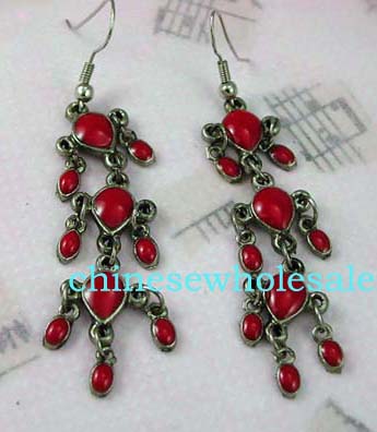 China jewelry suppliers exporting gemstone wholesale earrings. Dangling earrings with two small oval red gemstones hanging beside each of the three large red stones suspended below fish hooks.