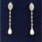 Jewelry accessory importing company distributes gemstone earrings to retailers. Beautiful imitation pearls suspended from oval rhodium plated studs by chain with cz stones.