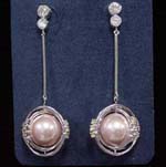 Wholesale jewelry supply company distributes China manufactured crystal gifts. Two clear cz chrystals hold rhodium plated poles that suspend a large pink imitation pearl surrounded by rhodium plated circles with yellow cz stones on each side