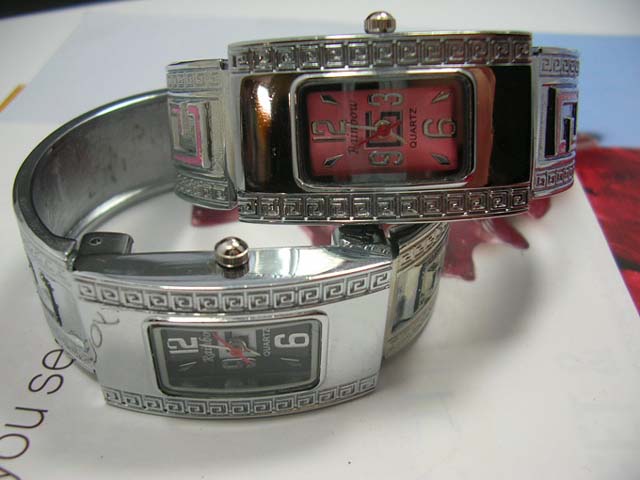 Metallic wear silver watch with G letter on bangle bracelet and square spiral theme on frame of clock face. Watches online wholesale