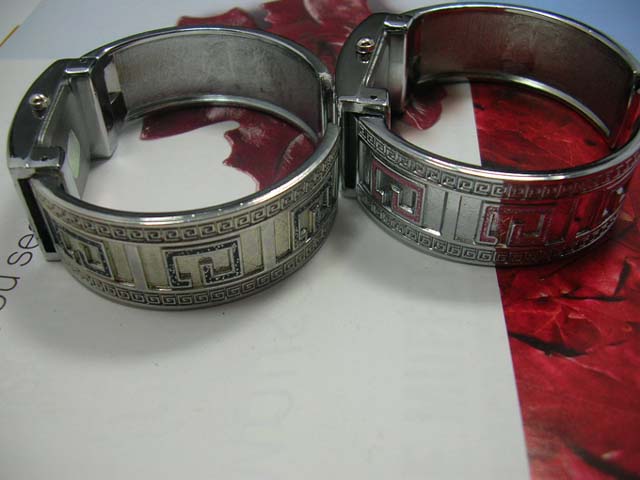 Metallic wear silver watch with G letter on bangle bracelet and square spiral theme on frame of clock face. Watches online wholesale